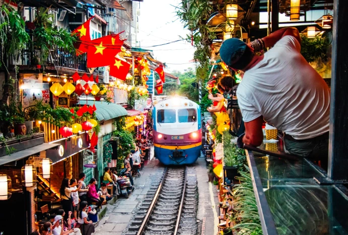 Vietnam train traveling down train tracks next to a crowd of people